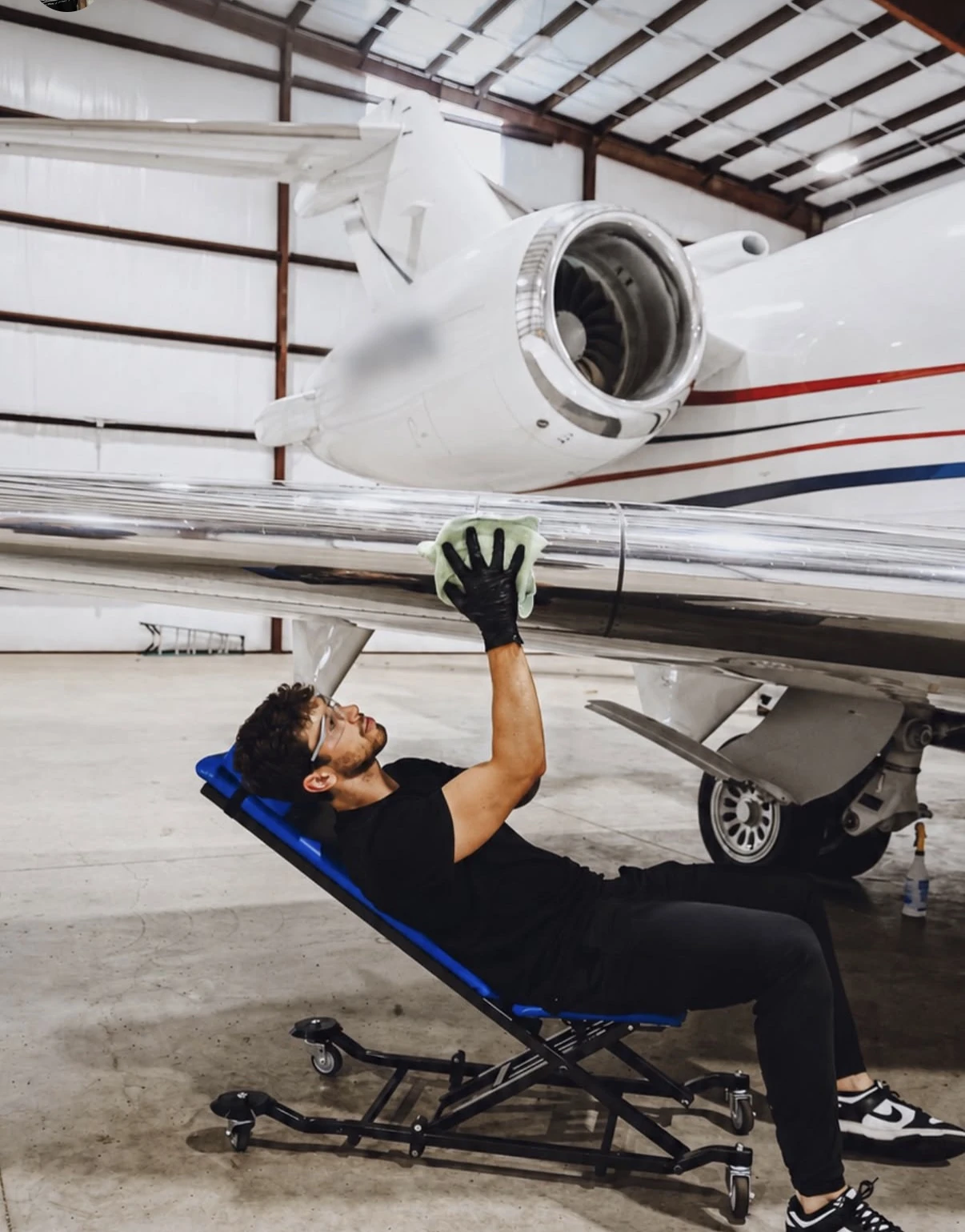 Technician cleaning the underside of an aircraft wing during a detail
